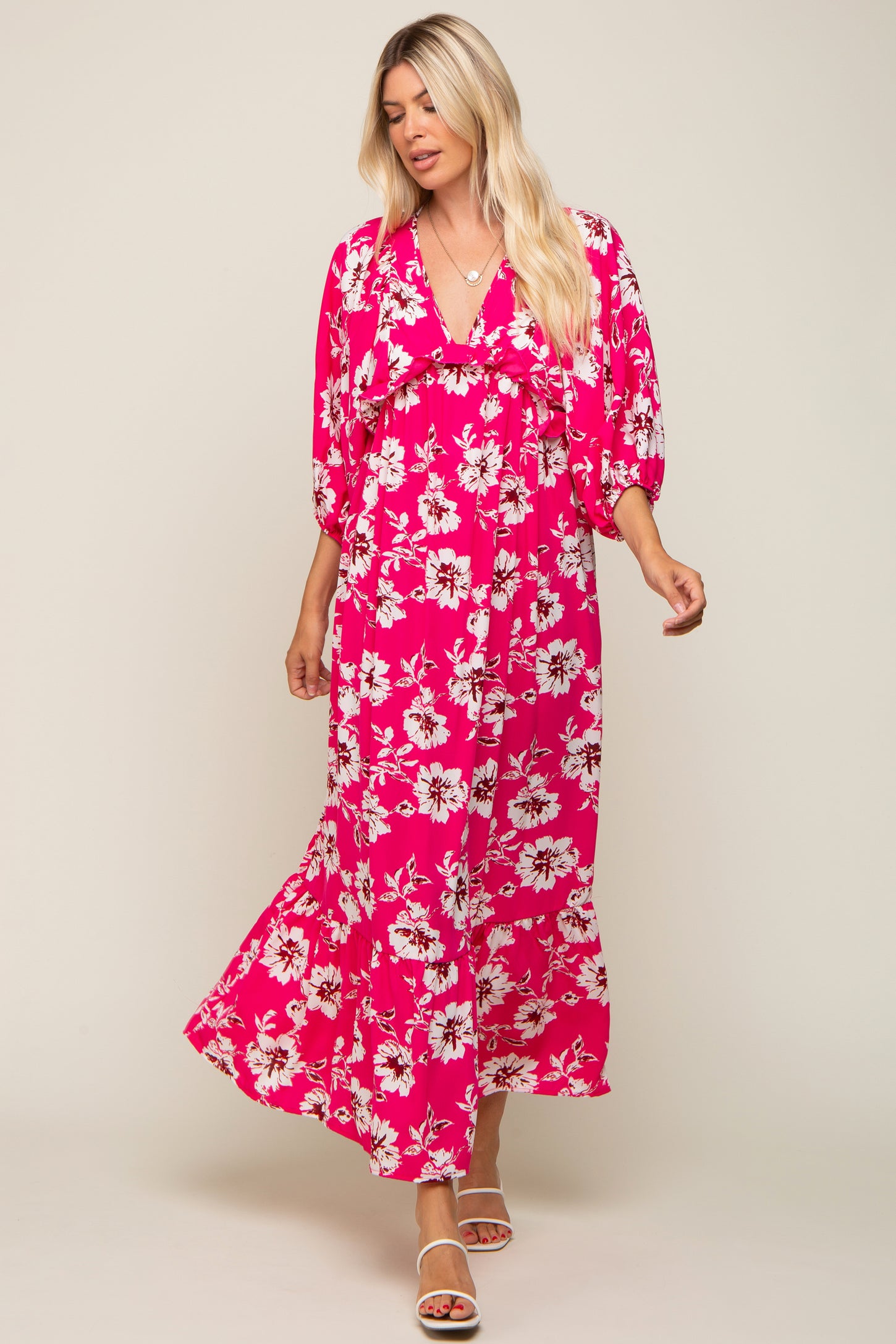 woman wearing a pink floral maxi dress with a v-neck and puff sleeves, standing in a relaxed pose