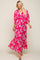 woman wearing a pink floral maxi dress with a v-neck and puff sleeves, standing in a relaxed pose