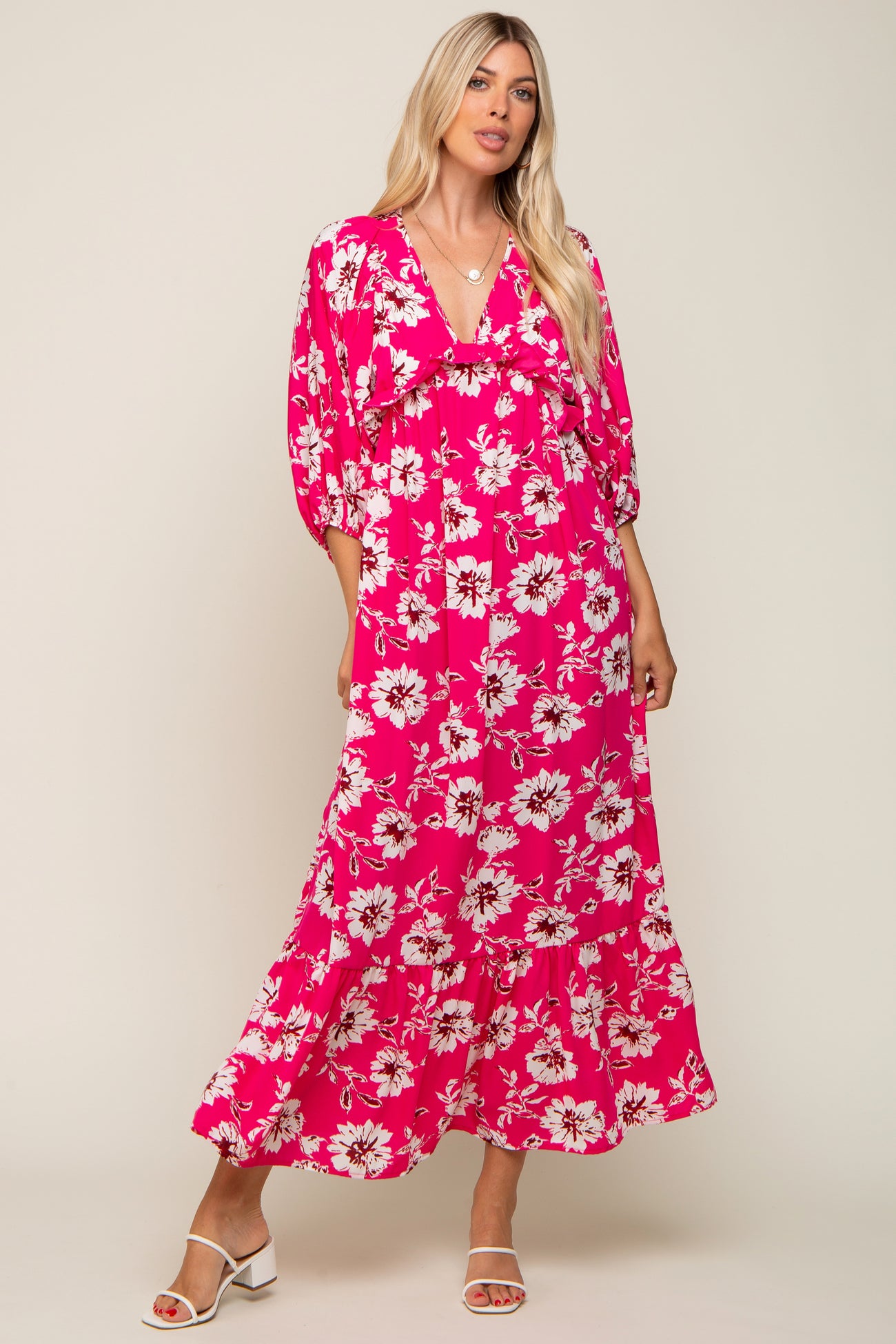 woman wearing a vibrant pink floral maxi dress with puff sleeves and a ruffled hemline