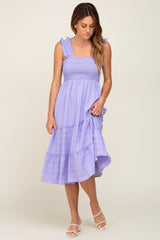 Woman wearing a lavender smocked midi dress with ruffled straps and a tiered skirt