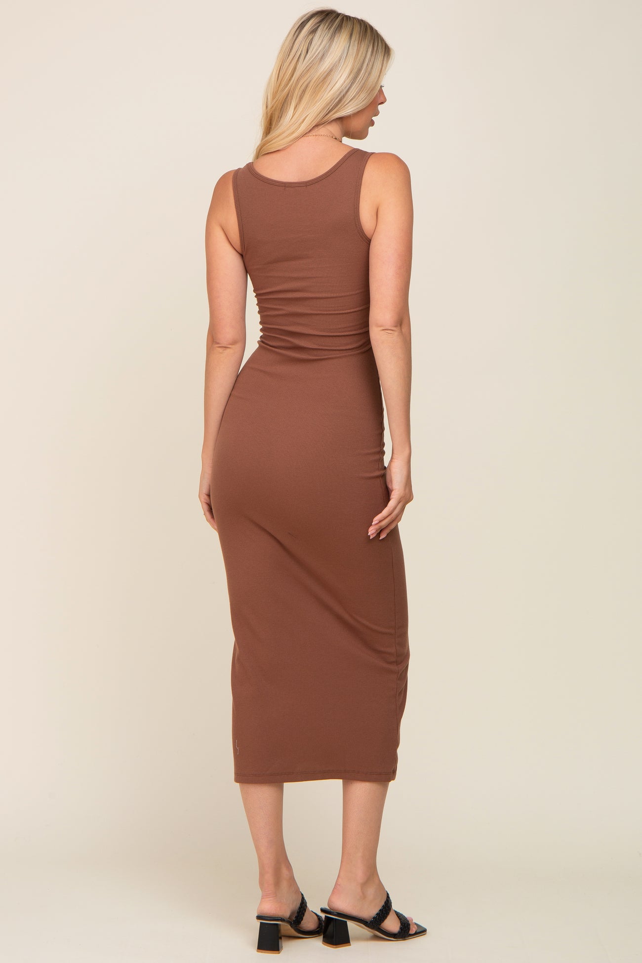Back view of a blonde woman wearing a brown ribbed midi tank dress and black heeled sandals