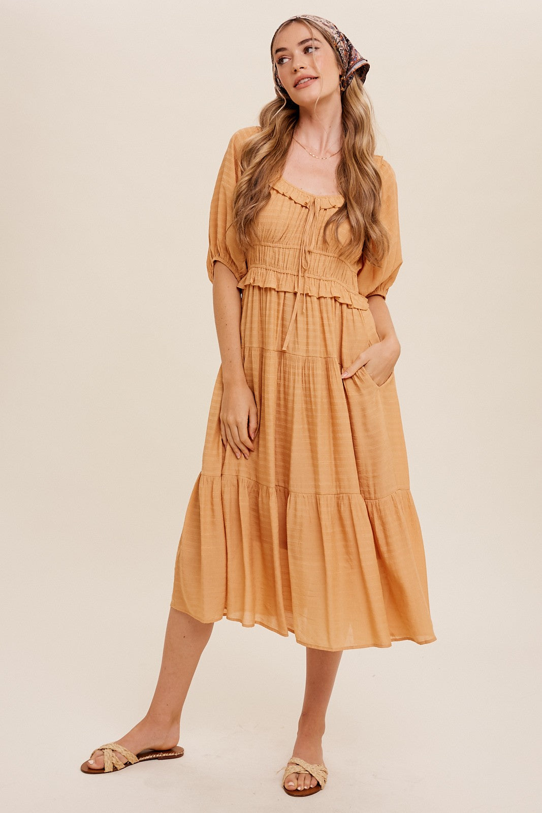 woman wearing a mustard yellow tiered midi dress with puff sleeves and a headscarf
