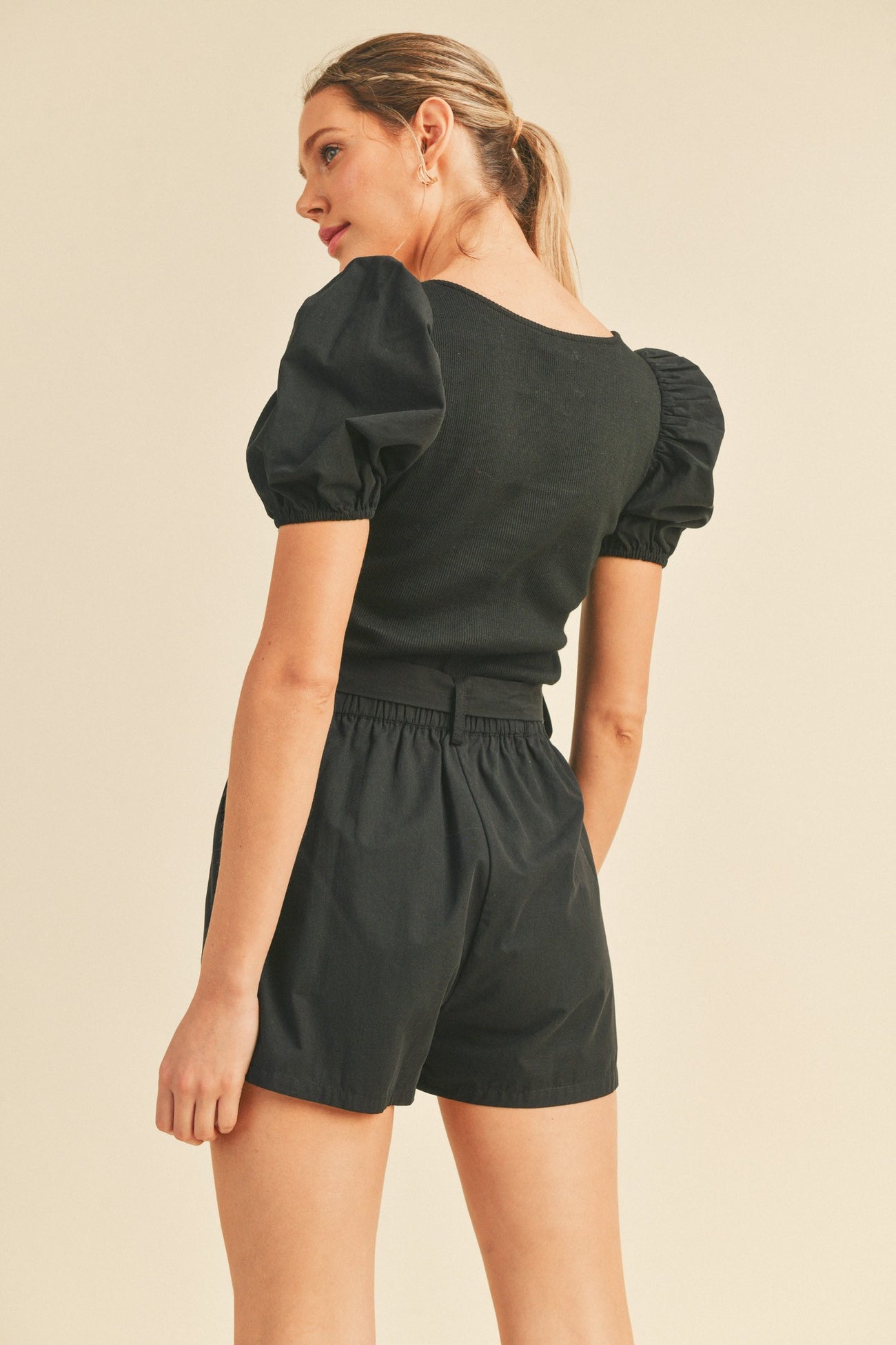 woman wearing black puff sleeve top and matching high waisted shorts viewed from the back