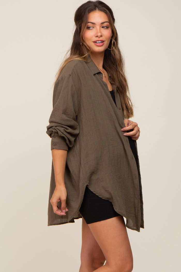 woman wearing an olive green oversized button down maternity shirt over a black dress