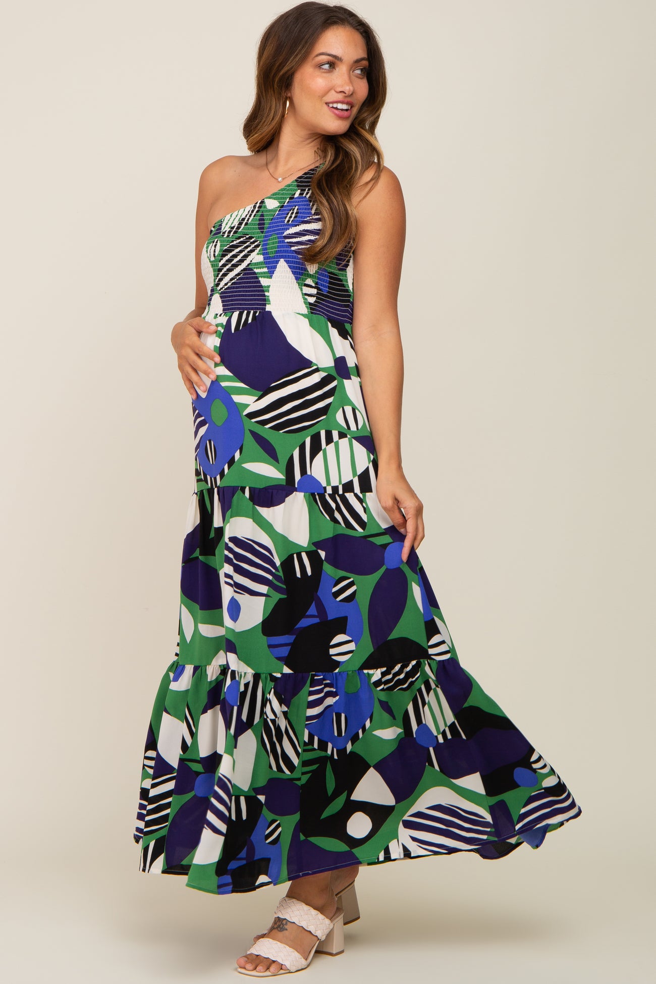 woman wearing a colorful patterned maternity maxi dress, showing her baby bump with a tiered skirt