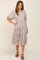 woman wearing a grey floral tiered midi dress with puff sleeves and brown platform sandals