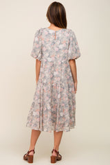 Back view of a woman wearing a grey floral tiered midi dress with puff sleeves and brown clogs