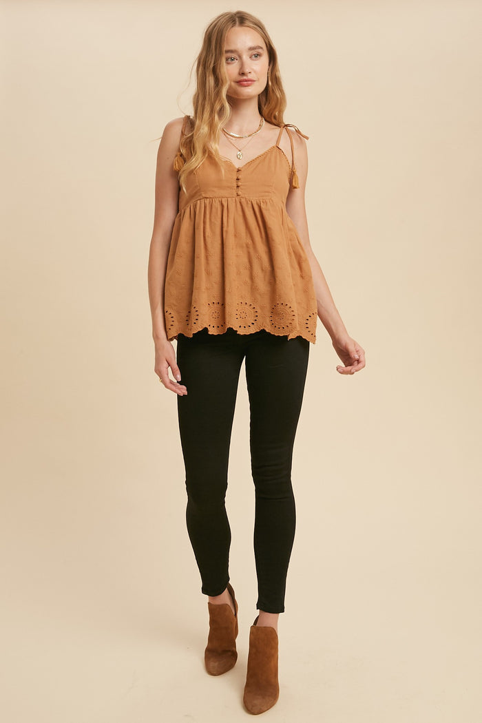 woman wearing a tan eyelet babydoll tank top with black skinny jeans and brown suede ankle boots