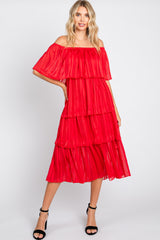 woman wearing a red off-the-shoulder tiered midi dress with flowing layers and black strappy heels