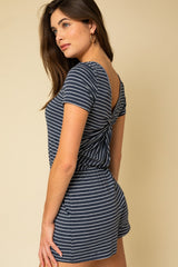 woman wearing a navy blue and white striped short sleeve romper with a twist back detail