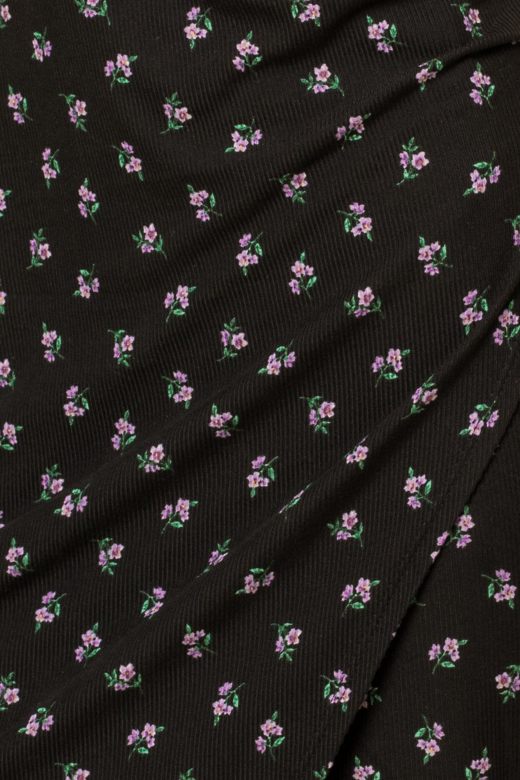 close up of black ribbed fabric with small purple floral print pattern