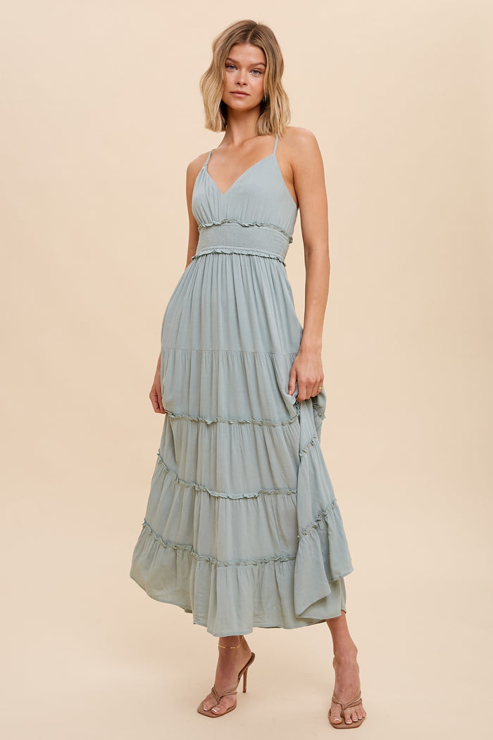 woman wearing a sage green tiered maxi dress with spaghetti straps and ruffled waist detail