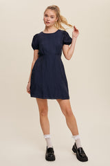 woman wearing a navy blue puff sleeve mini dress with white lace socks and black platform loafers