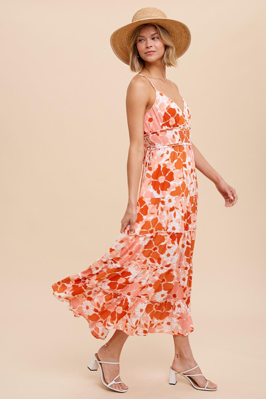 woman wearing orange and white floral tiered maxi dress with straw hat and white strappy heels