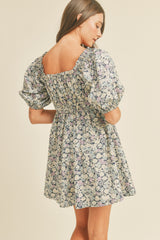 Woman wearing a floral puff sleeve mini dress with a smocked back and square neckline