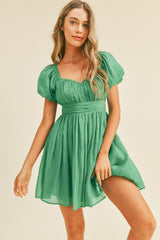 woman wearing a green puff sleeve mini dress with a sweetheart neckline and pleated skirt