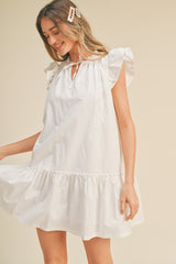 woman wearing a white ruffled short sleeve mini dress with a tie neck detail and a flared hem