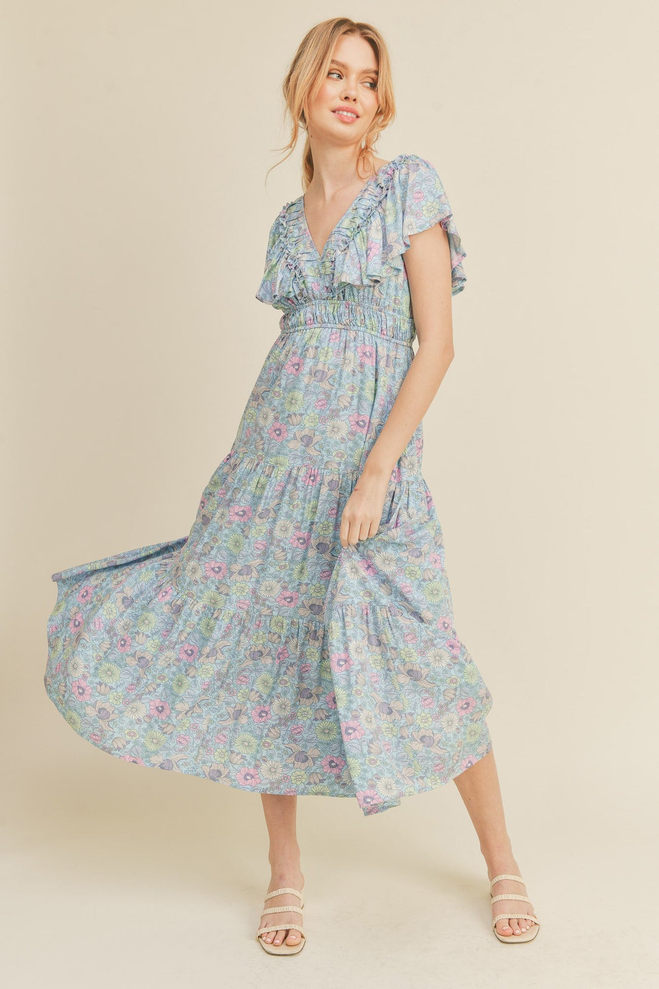 woman wearing a floral maxi dress with short ruffled sleeves and a v-neckline, standing in a light and airy pose