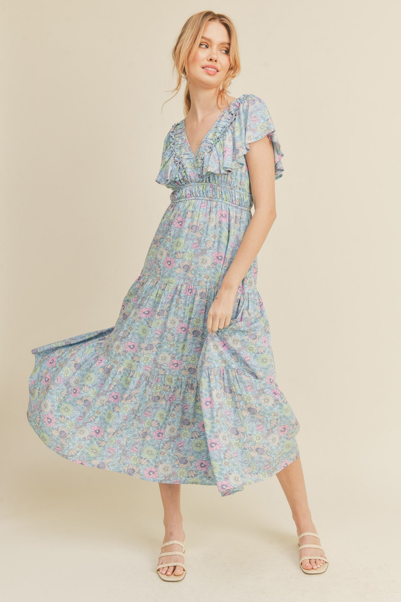 woman wearing a floral maxi dress with short ruffled sleeves and a v-neckline, standing in a light and airy pose