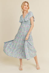woman wearing a floral maxi dress with short ruffled sleeves and a v-neckline, standing in a light and airy pose