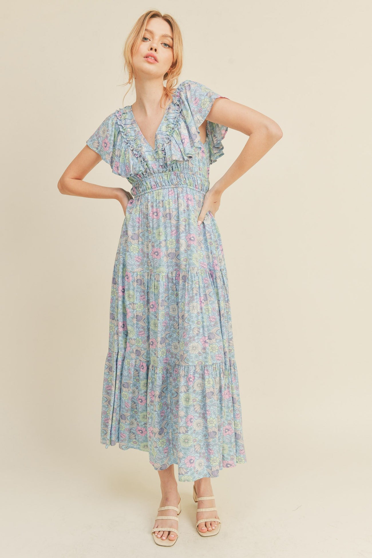woman wearing a floral print maxi dress with short flutter sleeves and a smocked waist