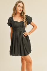 woman wearing a black short puff sleeve dress with a square neckline and a fitted waistline