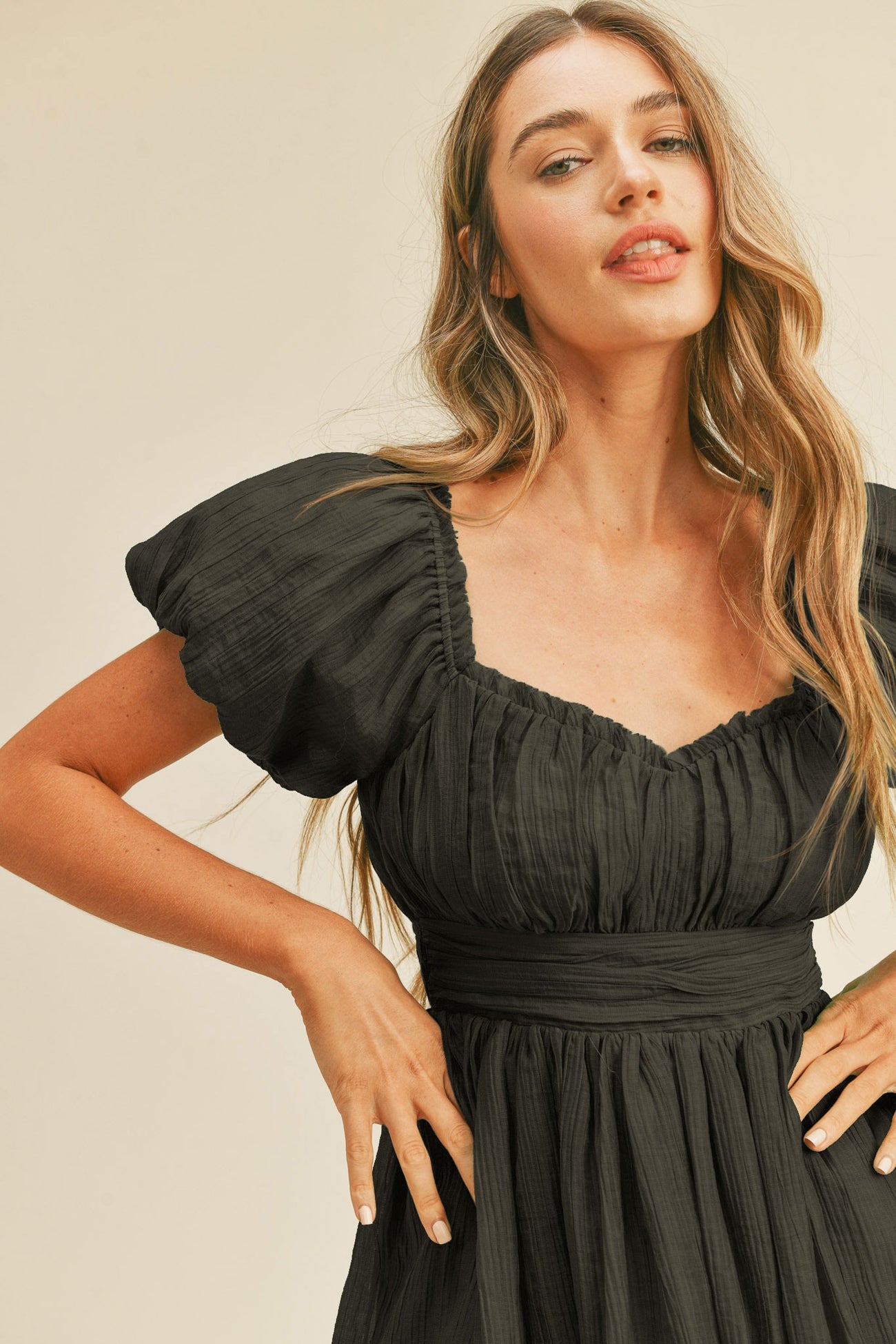 woman wearing a black puff sleeve dress with a fitted waist and gathered bodice