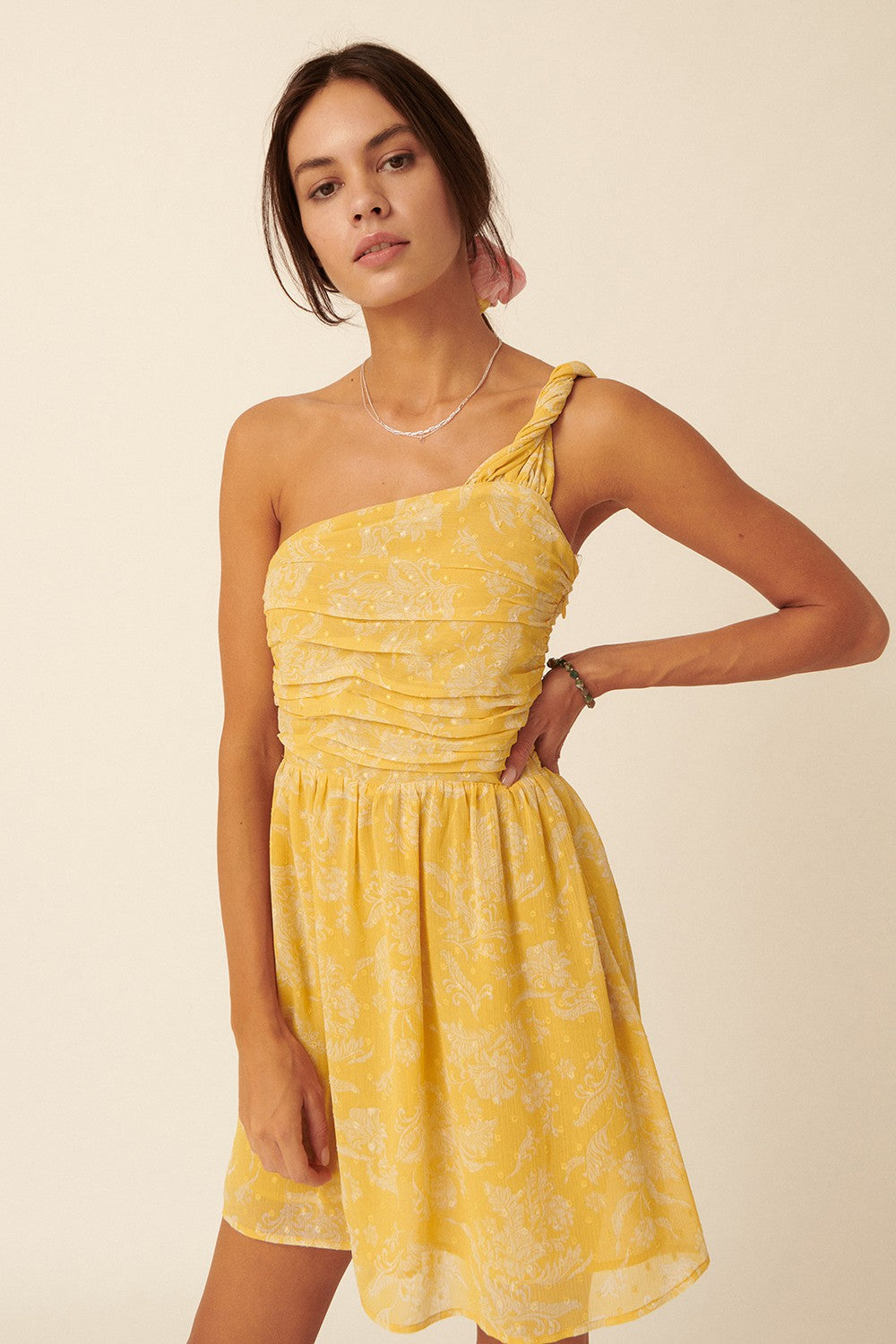 woman wearing a yellow one-shoulder dress with a ruched bodice and floral pattern