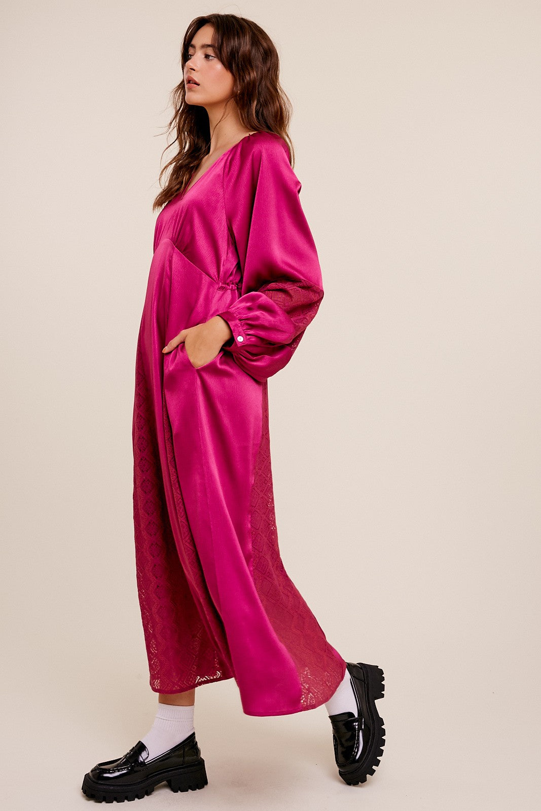 woman wearing a bright pink long sleeve maxi dress with pockets and lace detail, styled with black platform shoes
