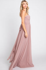 woman wearing a strapless blush pink maxi dress with a ruched bodice and flowing skirt