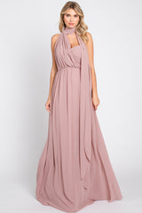 woman wearing a long blush pink maxi dress with a draped bodice and scarf detail