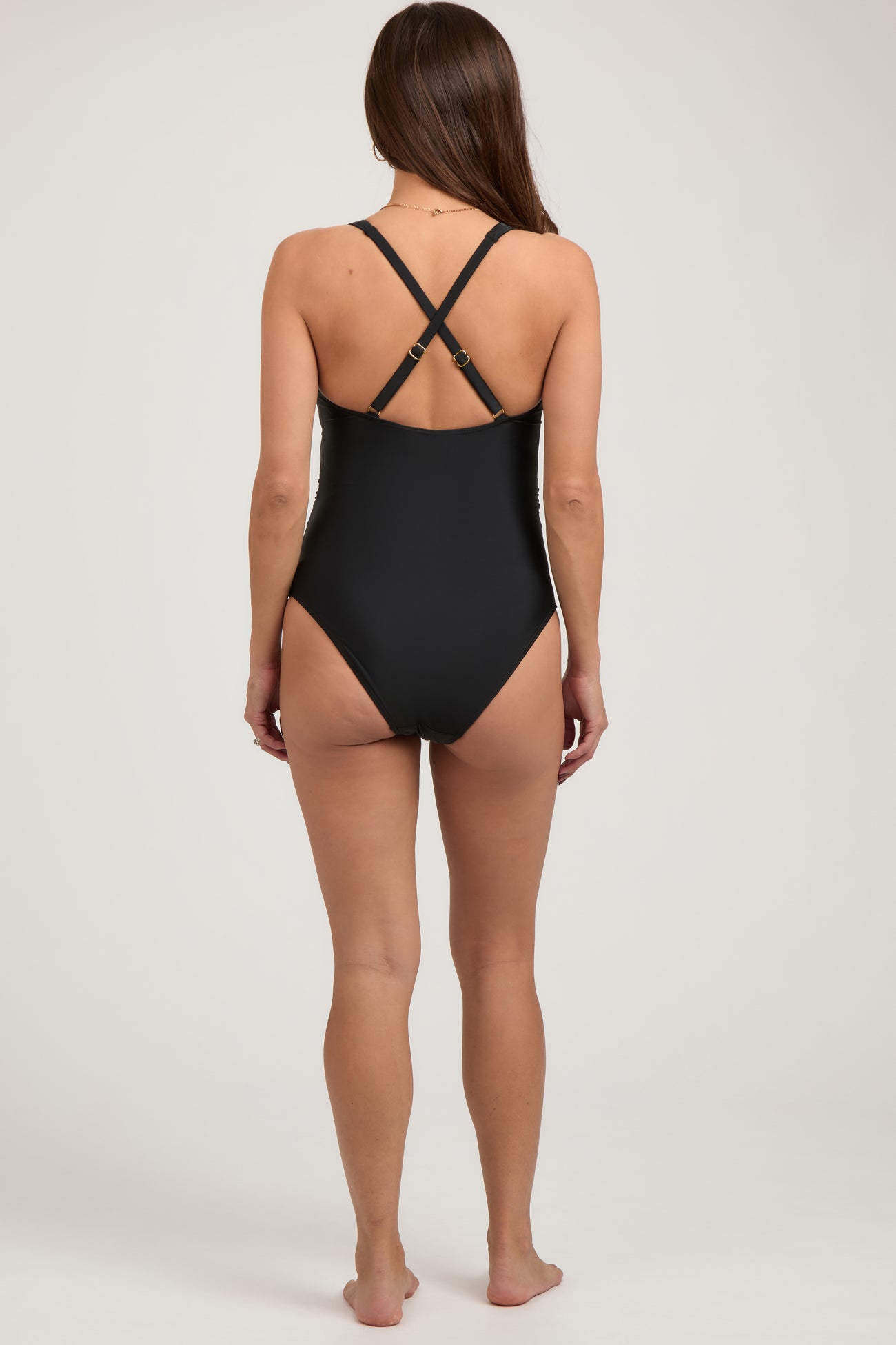 woman wearing a black maternity swimsuit with crisscross straps, showing the back view
