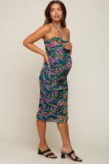 woman wearing a colorful floral strapless maternity dress, showcasing her baby bump and styled with black heels