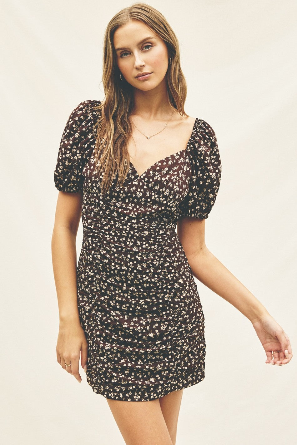 woman wearing a black floral mini dress with puff sleeves and a ruched bodice