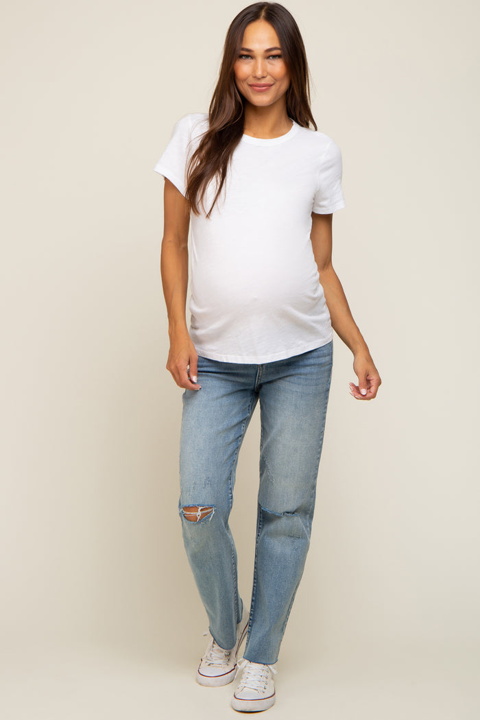 pregnant woman wearing a white maternity t-shirt and distressed blue jeans with white sneakers