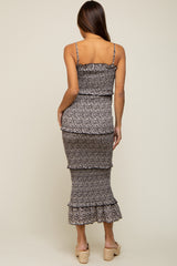 woman wearing a black and floral print maternity dress with a fitted silhouette and ruffles at the hem, standing sideways