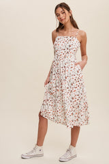 woman wearing a white floral midi dress with spaghetti straps and pockets, paired with white high-top sneakers