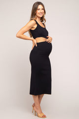 woman wearing a black maternity dress with cut-out details and holding her baby bump