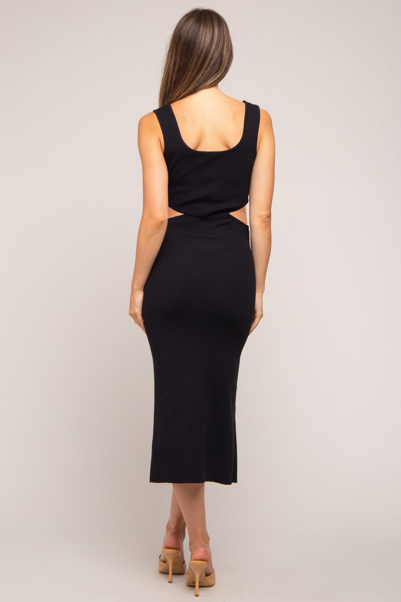 woman wearing a black ribbed maternity dress with a cut-out detail and a fitted silhouette