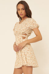 woman wearing a cream floral print short dress with puff sleeves and side cutouts