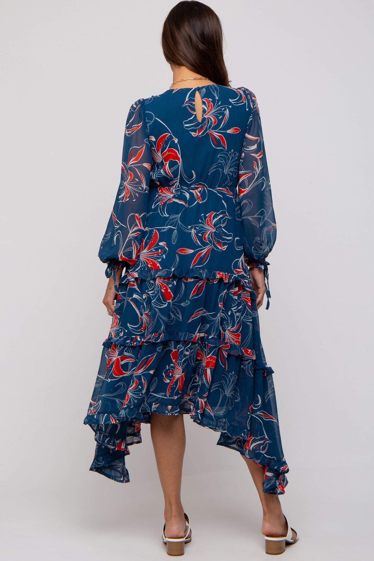 woman wearing a navy blue floral maternity dress with long sleeves and a tiered ruffle hemline