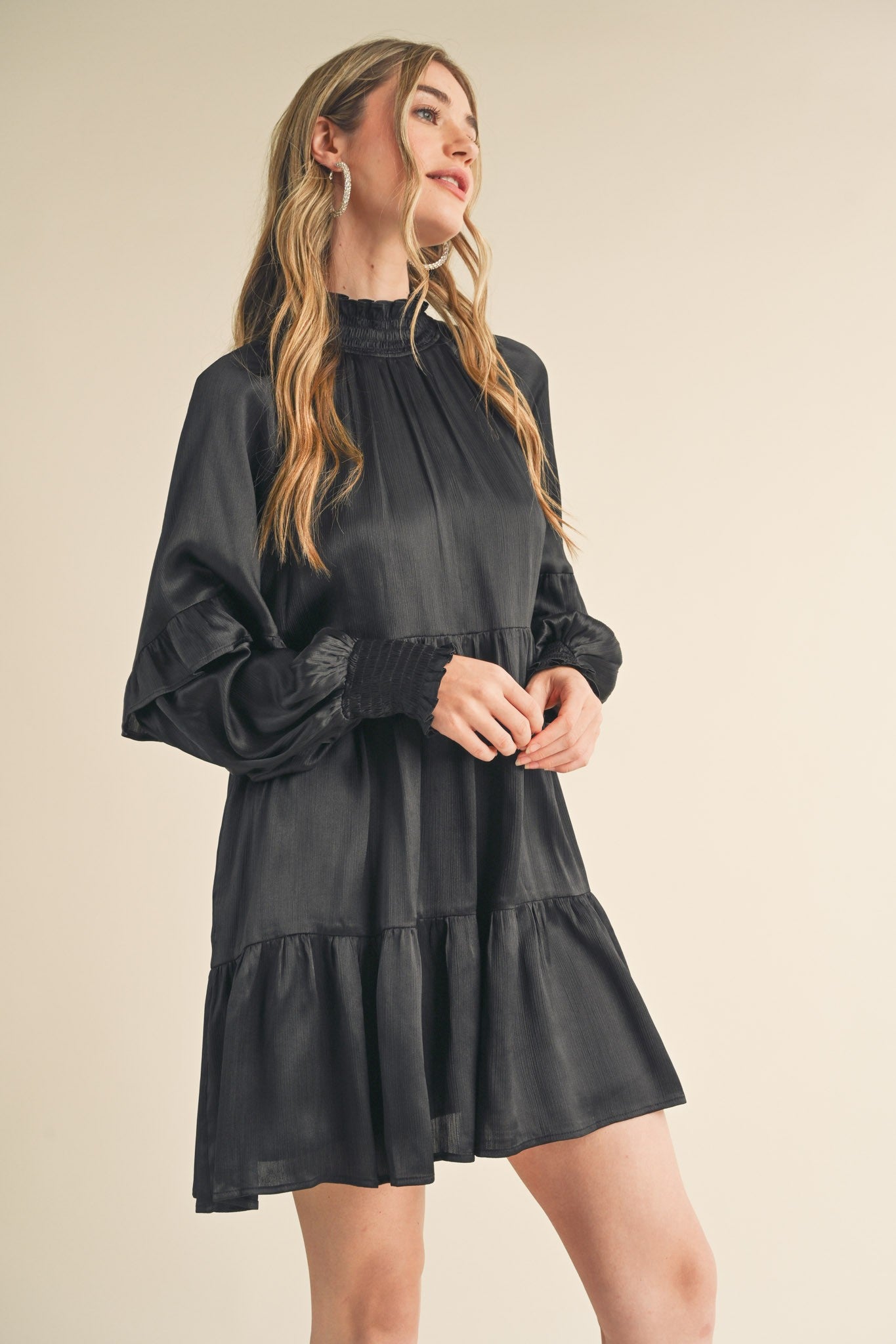 woman wearing a black long sleeve tiered dress with a high neckline and puffed sleeves