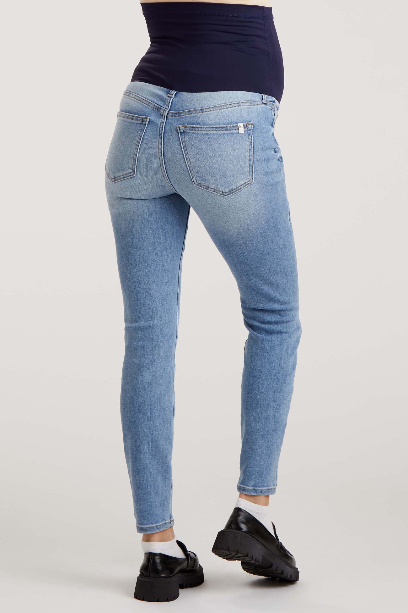 maternity wear light blue skinny jeans with a stretchy waistband, model showing a baby bump from the back