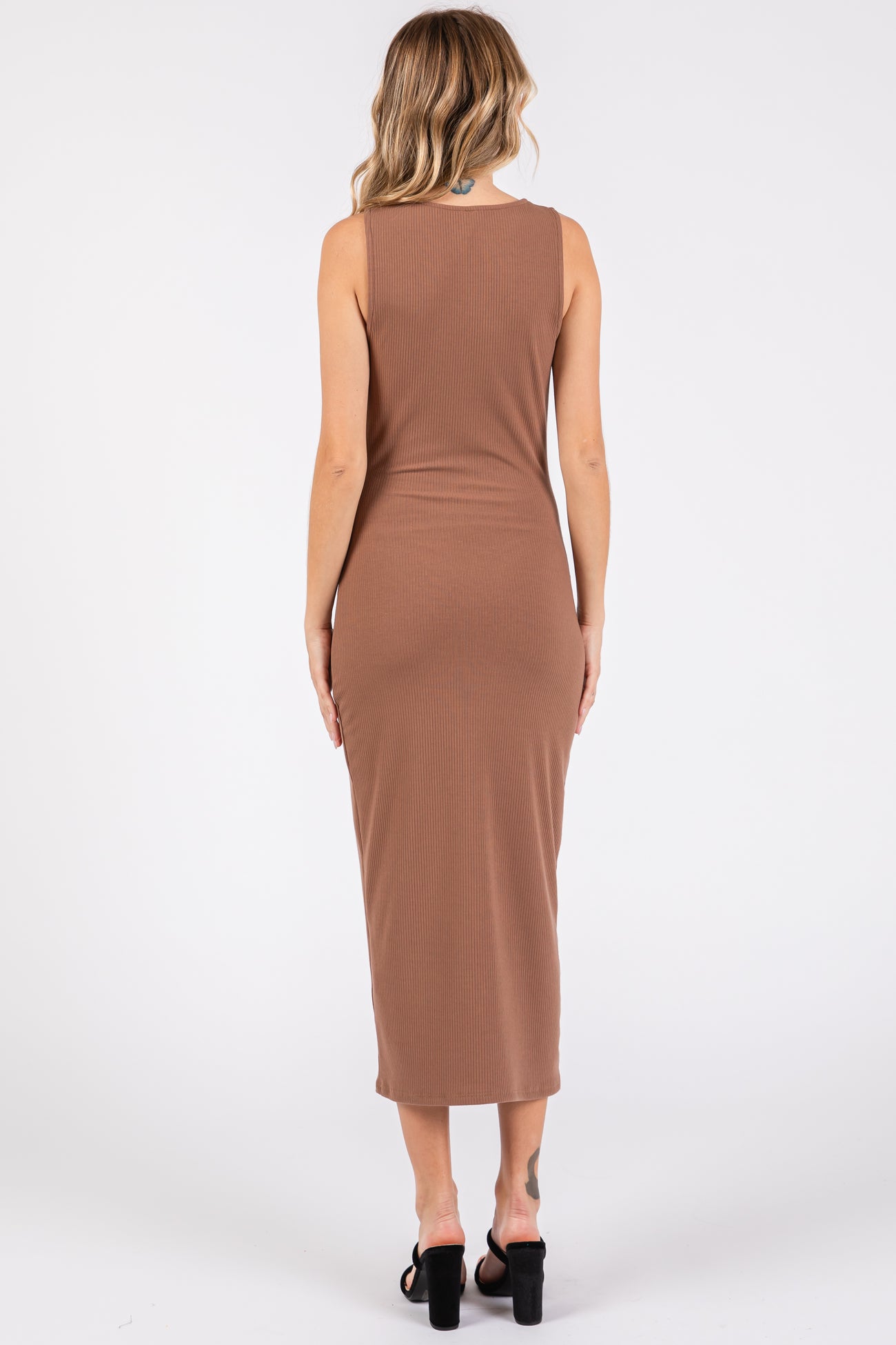 woman wearing a fitted brown ribbed maxi dress, showing the back view and styled with black heeled sandals