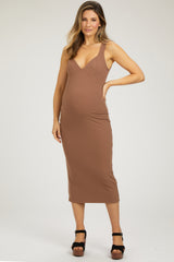 woman wearing a brown maternity dress with a fitted silhouette and spaghetti straps, showcasing her baby bump