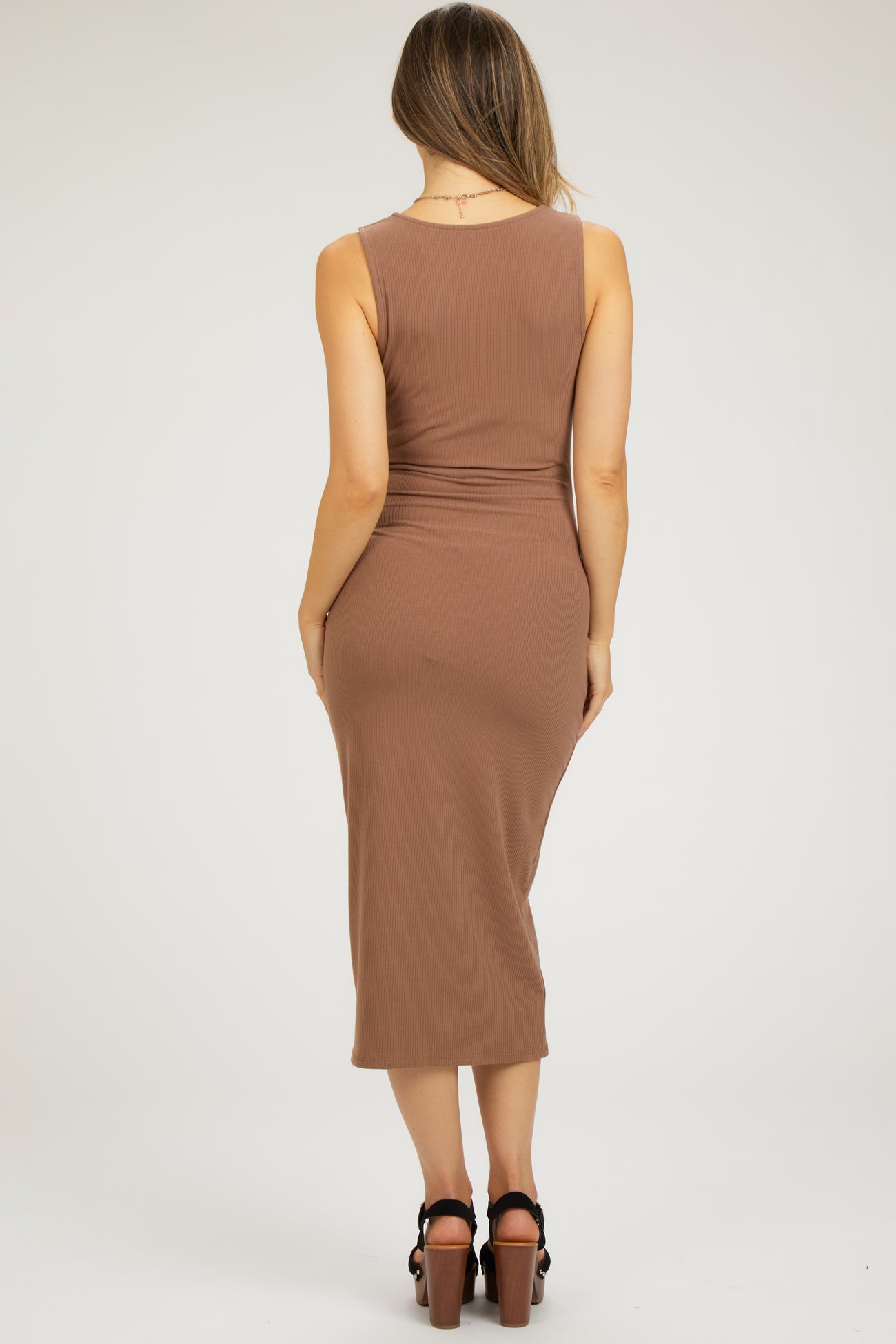 woman wearing a brown ribbed maternity dress, view from the back, showing a fitted silhouette