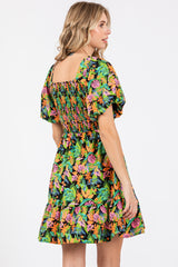 woman wearing a black floral smocked mini dress with puff sleeves, showing the back view