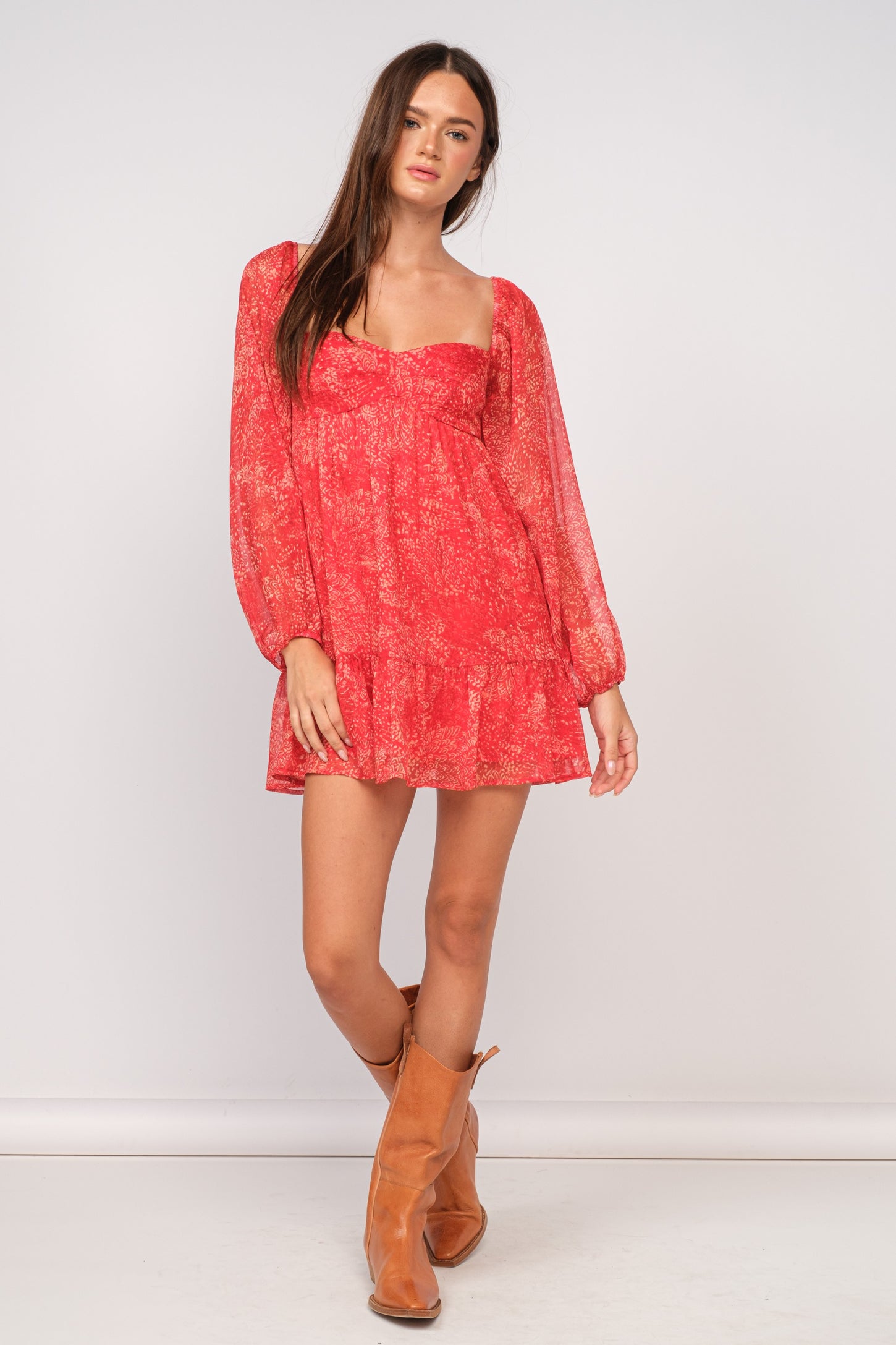 woman wearing a red floral long sleeve mini dress with a ruffled hem and tan ankle boots