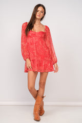 woman wearing a red floral long sleeve mini dress with a ruffled hem and tan ankle boots