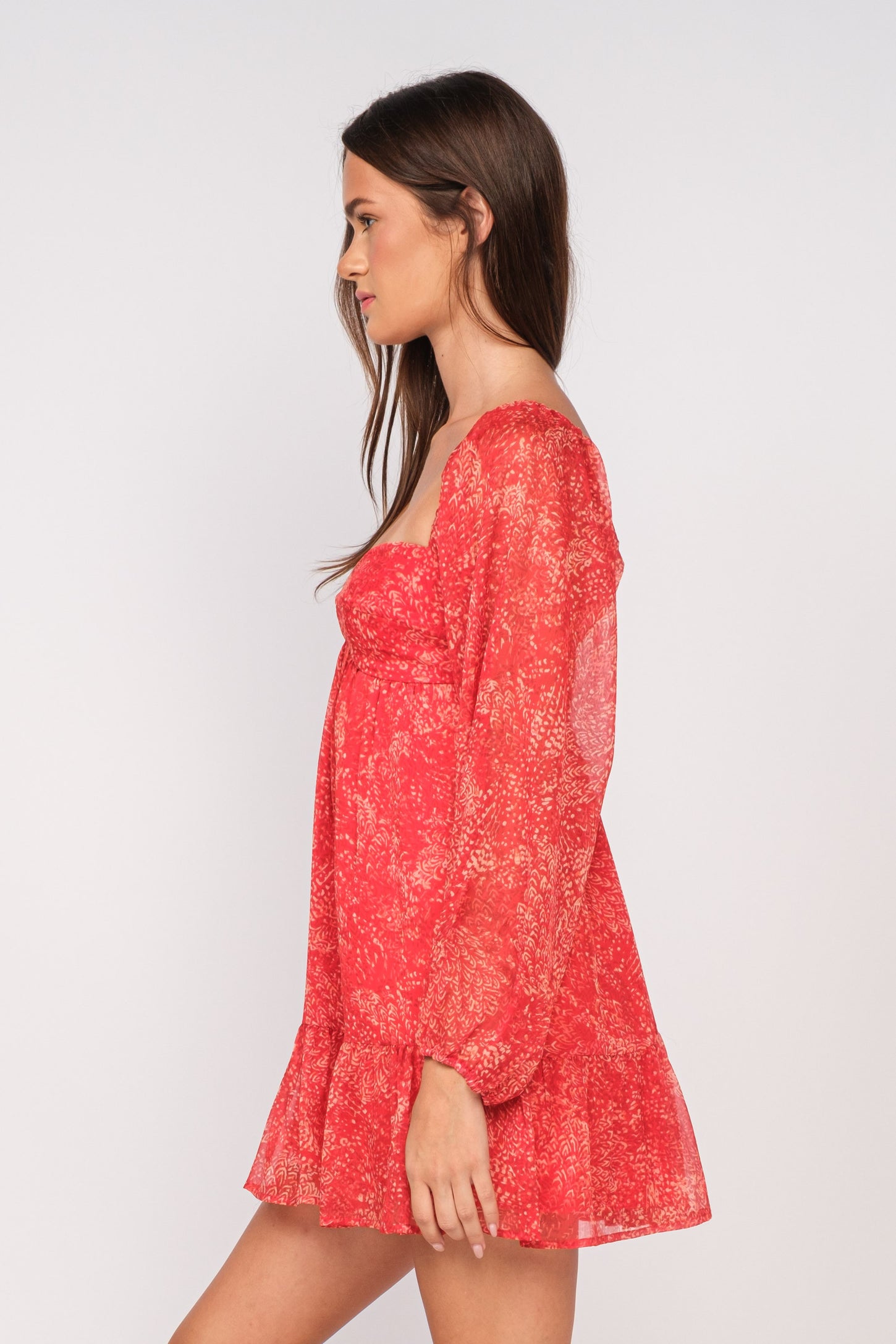 woman wearing a red floral long sleeve mini dress with ruffled hem, shown from the side